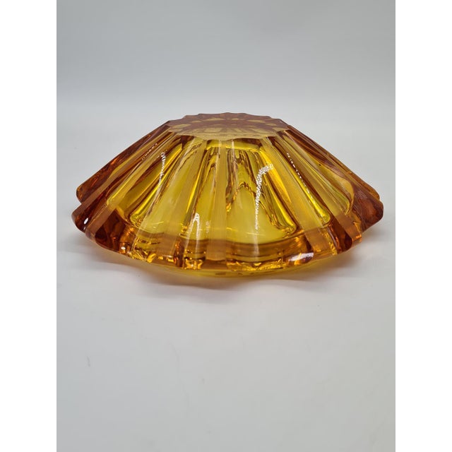 A striking bowl crafted from thick, pressed glass in a beautiful amber (honey) color. Its distinctive, radiant form with...