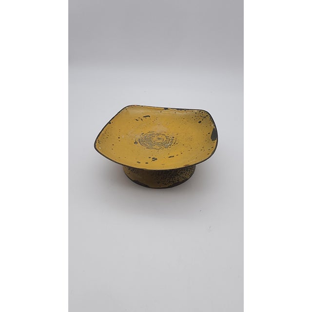 Small square-form pedestal dish featuring a vivid mustard yellow enamel interior with abstract black speckling and...