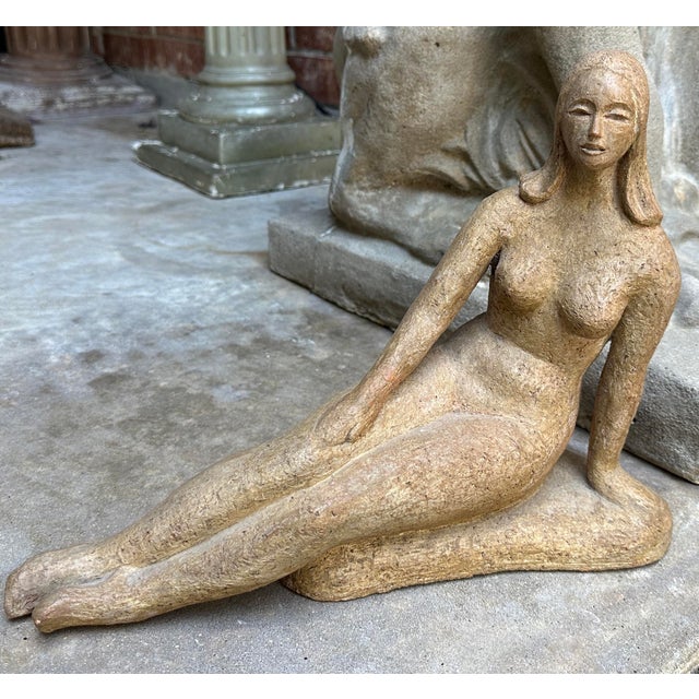 A sculptural mid-century modern cast stone figure depicting a reclining female form in a relaxed, contemplative pose. The...