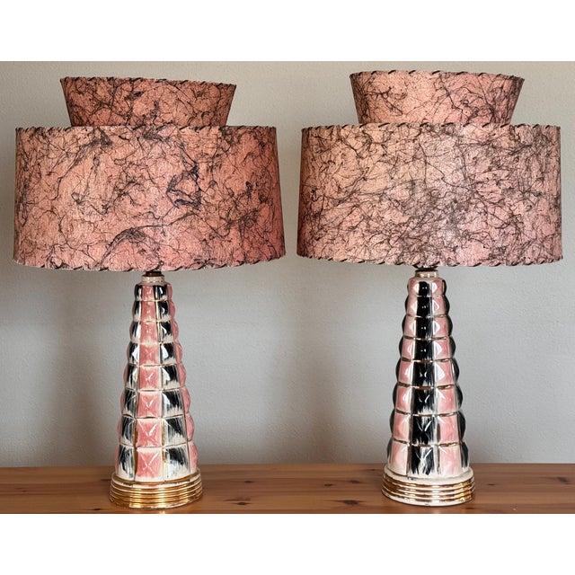 Presenting a pair of authentic Mid-Century ceramic lamps in Atomic Era pink and black with gold accents. It is rare to...