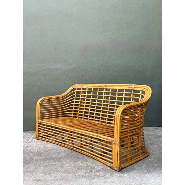 This vintage stacked rattan sofa brings the easy lines of mid-century tropical design to a compact seating piece. Honey-...