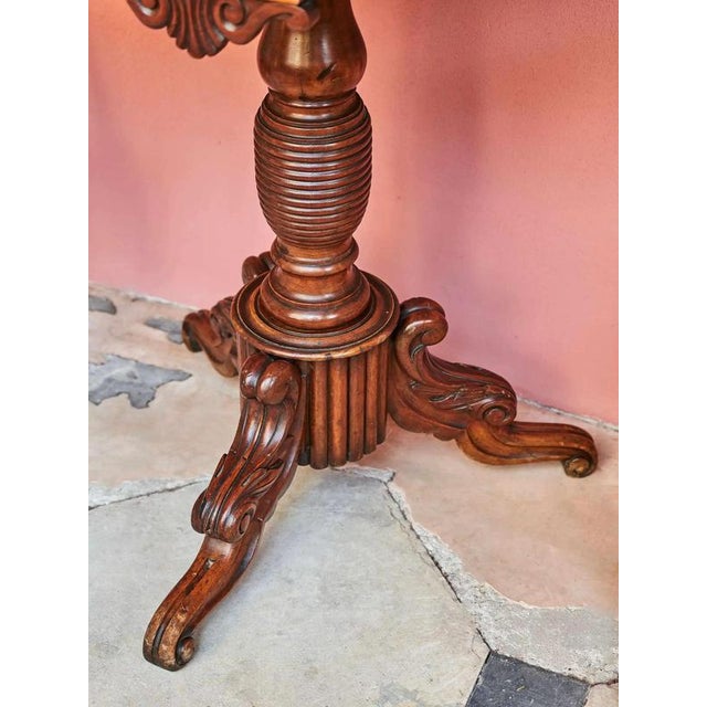 Hand-carved 19th century game table on a central leg divided by a tripod. Fine floral carving. Inside the table is a...