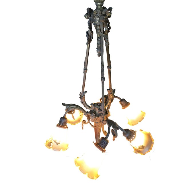 A French Louis XVI style four-light bronze chandelier with scrolling arms, garlands and floral-shaped shades. Suspended...