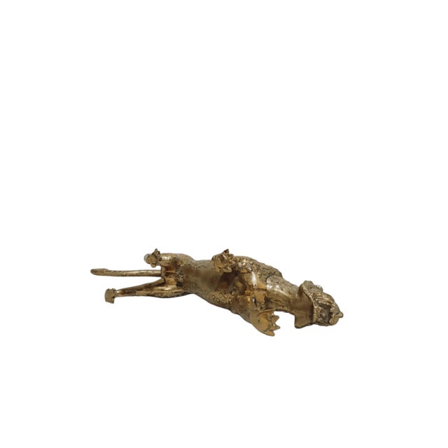 A long, low vintage leopard sculpture in brass-toned metal, caught mid-stride with one foreleg extended and its mouth...