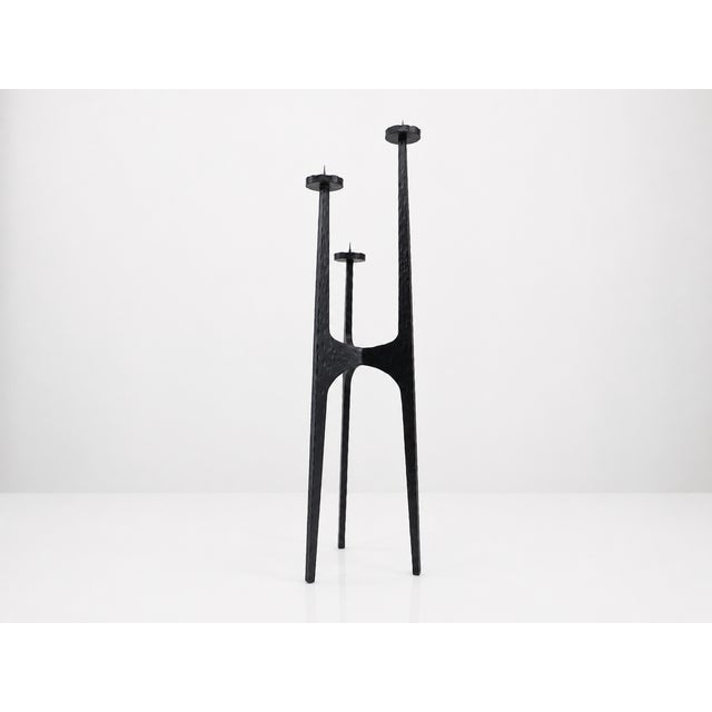Large tripod candlestick in hammered wrought iron, made in Europe around the 1960s. Its architectural silhouette is...