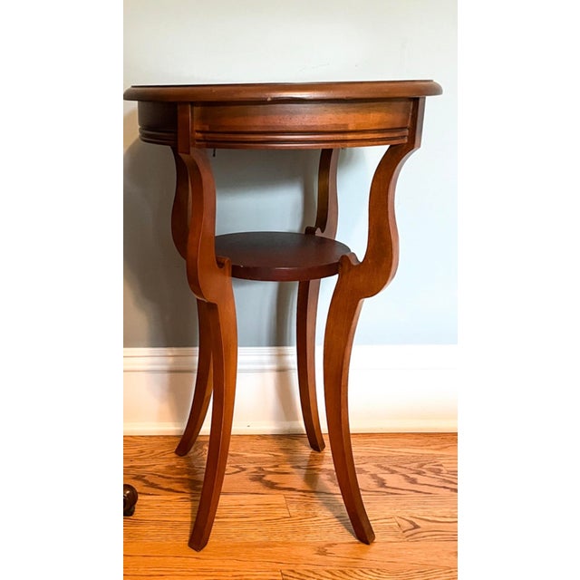 A vintage round two-tier mahogany side table with a wide banded border of lighter, straight-grained mahogany veneer with a...
