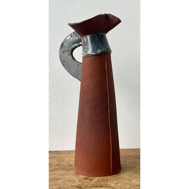 This striking studio pottery pitcher is a masterful example of mid-century Brutalist design, offering an authoritative...