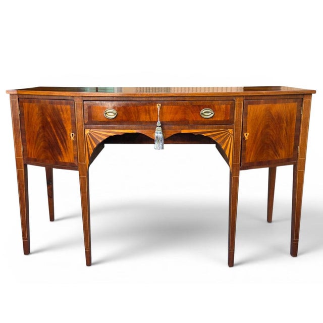 An elegant English Regency sideboard crafted in richly figured mahogany and embellished with refined satinwood line inlay...