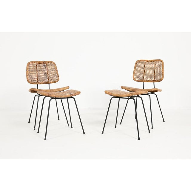 Elegant pair of Mid-Century Modern chairs with stools from 1960’s with black painted steel frame and wicker seat....