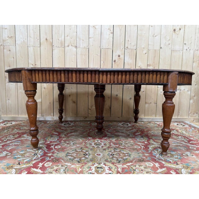 Solid wood oval dining table, composed of two interlocking half-tabletops, resting on six turned baluster legs...