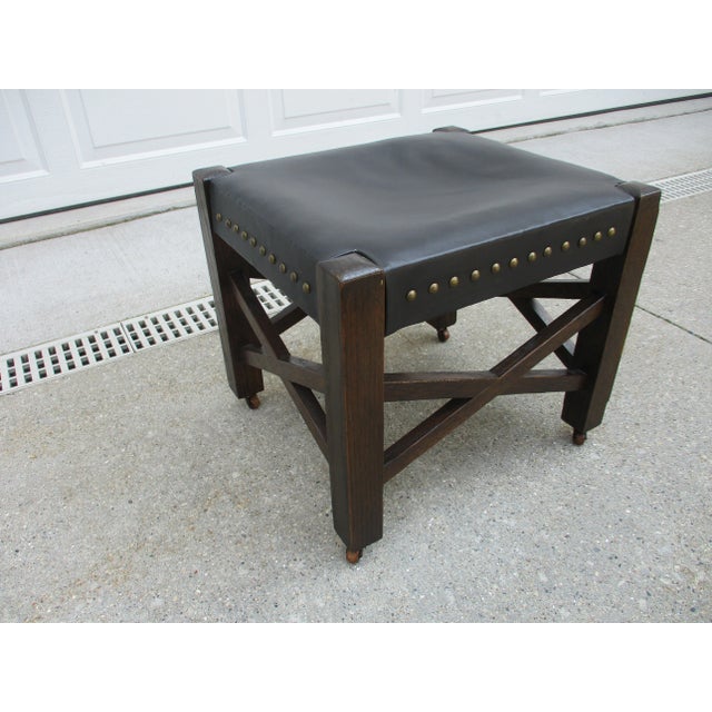 This low stool or footstool has that wonderful Arts & Crafts, Mission style look. The black leather with the brass-colored...