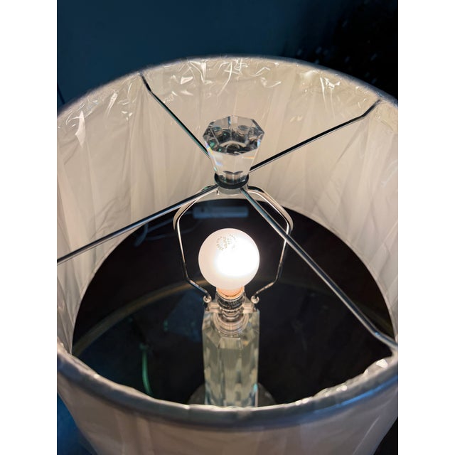 A table lamp by Haig featuring a solid crystal body with brass nickel-plated polished accents. Finished with an off-white...