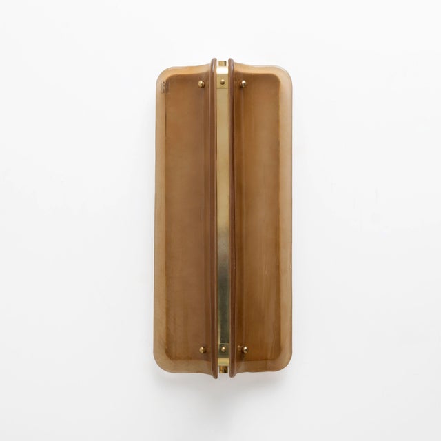 An elegant pair of italian big sconces composed of curved murano glass panels in a refined shade of amber. the curved...