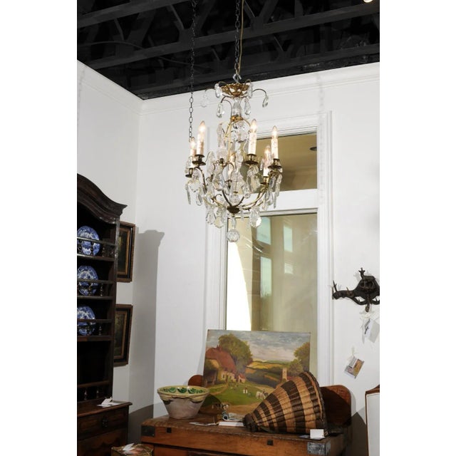 A French six-light crystal chandelier from the 19th century, with brass armature, pendeloques and round finial. Born in...