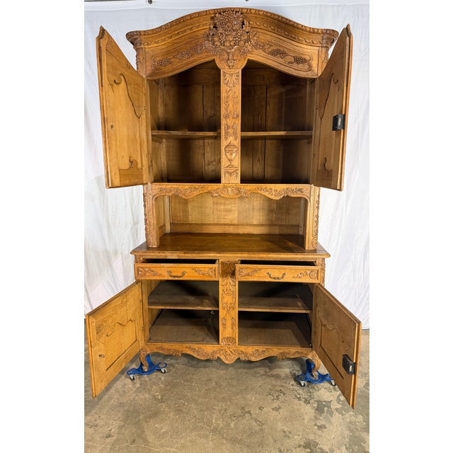 Heavily carved antique French oak 1840's cupboard featuring intricate floral and grapevine carvings. Upper section...