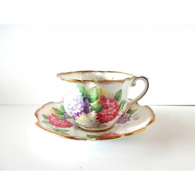 A vintage teacup and saucer set with pink, purple, and white lilacs. Marked: Royal Stafford Bone China, "Carousel", Made...