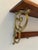 Vintage 1970s wall-mounted shelf featuring substantial cast metal scroll brackets in a warm aged brass-tone finish and...