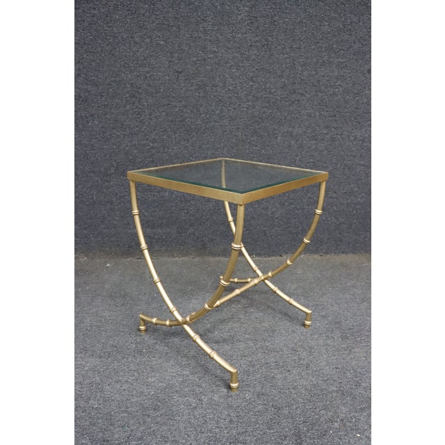 Square side table with a clear glass top and bamboo-style curved legs joined by an X-base.