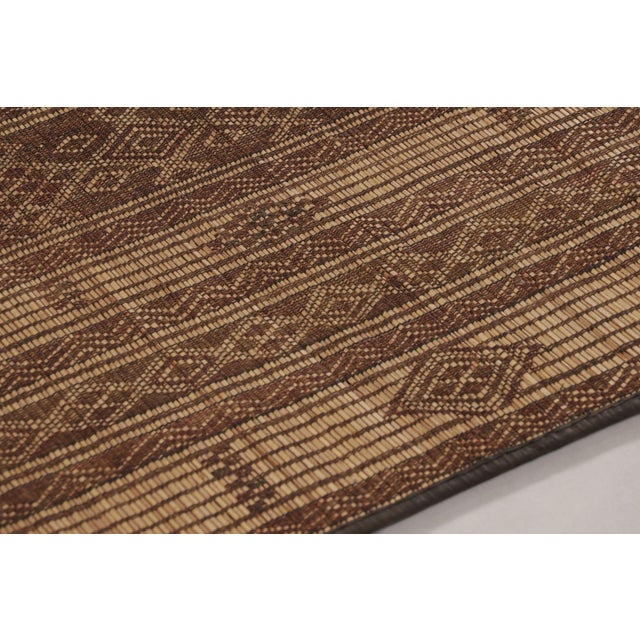 Made with handwoven reed and camel leather in Mauritania circa 1950-1960, this 3x5 vintage Tuareg mat is an exceptional...