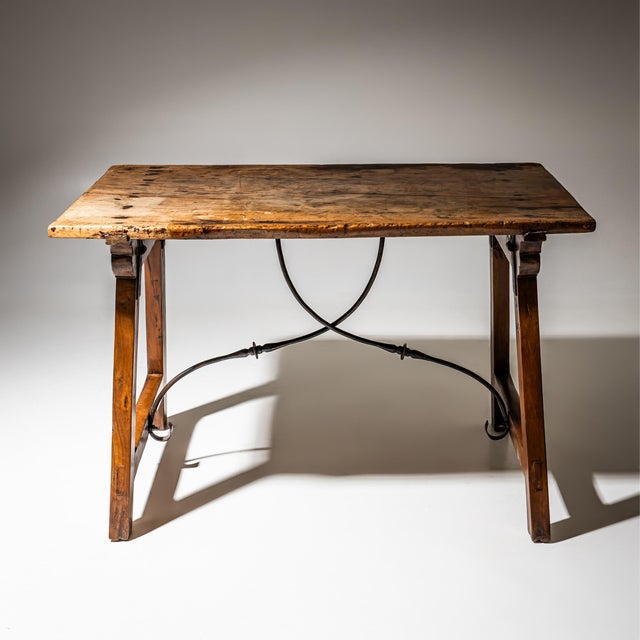 Rectangular walnut table with a nicely patinated top. The legs are connected by a curved iron stretcher, adding both...