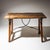 Rectangular walnut table with a nicely patinated top. The legs are connected by a curved iron stretcher, adding both...