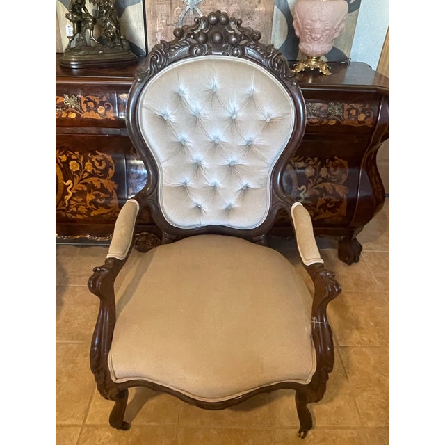 An elegant pair of Victorian Revival parlor chairs featuring richly carved dark wood frames, graceful silhouettes, and...