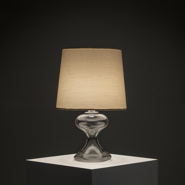 A sculptural table lamp by Ingo Maurer, executed in hand-blown clear glass and fitted with bespoke Rubelli fabric shades....