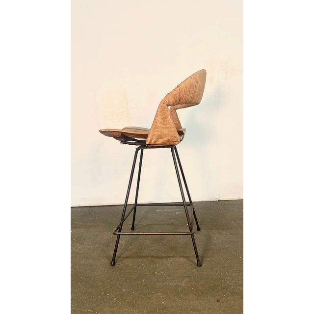 Here is a lovely barstool made from Iron, Rush, & slatted wood on a Swiveling base, Designed by Arthur Umanoff. It...