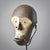 This striking mask, defined by its bold geometric contours and gracefully concave visage painted in a luminous white, is a...