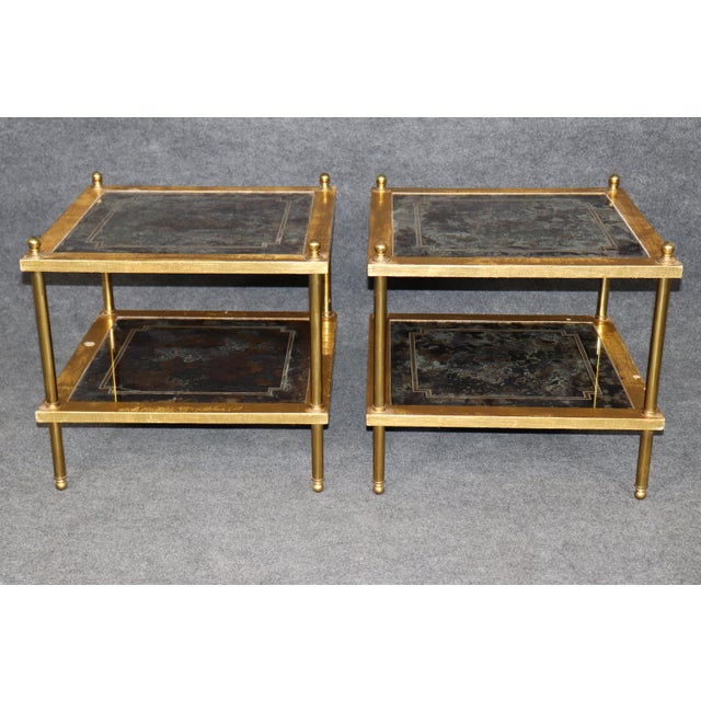 This sophisticated pair of églomisé brass and glass end tables embodies the timeless glamour of mid-century French luxury...