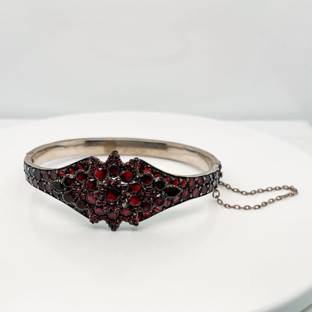 A very fine Antique Bohemian gold-filled bangle bracelet. Prong set with garnets in a flower pattern to the top and around...