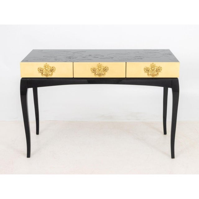 Boca Do Lobo Black Lacquer Console Table, the glass top with cut scrollwork above three gold-leaf lacquered drawers. 30.5"...
