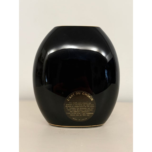 An elegant vintage Japanese porcelain vase from the 1970s, featuring the traditional Art of Chokin. The deep black...