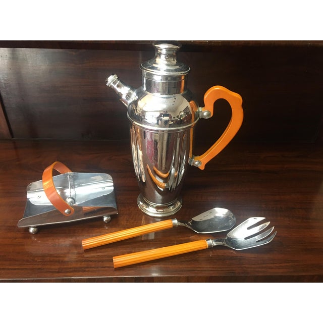 This handsome Art Deco period cocktail set features a large chrome spouted shaker, a napkin holder and two utensils. The...