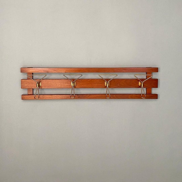 Italian Mid-Century Modern wooden slats structure and four brass hooks wall coat hanger. Elegant wall coat hanger, with...