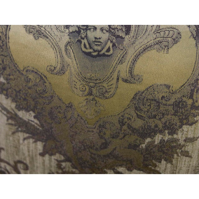 A woven textile piece featuring a prominent Medusa portrait surrounded by classical putti and intricate acanthus...