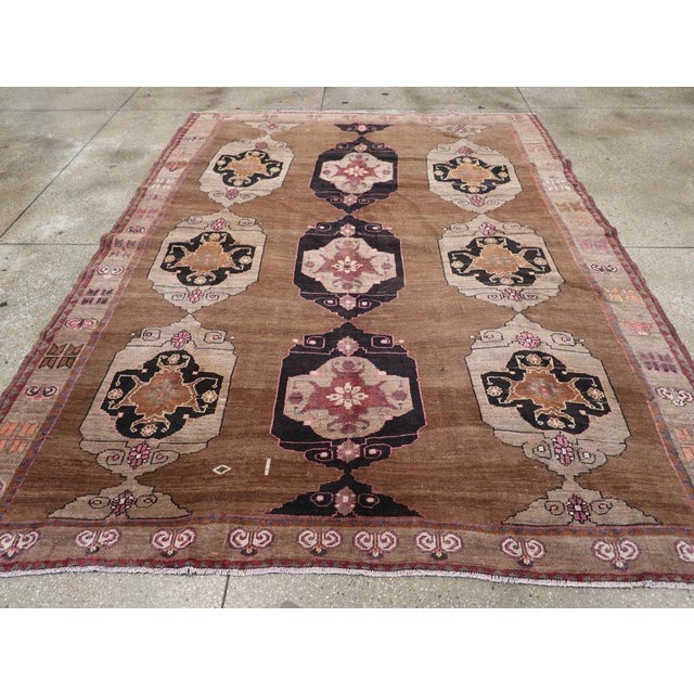 This mid-20th century Turkish Anatolian tribal carpet, measuring 7' 11" x 10' 6", presents a balanced and graphic layout...