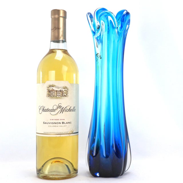 A ribbed turquoise blue glass has been stretched to over 12 inches. It has a rounded set of five crenelations at the top....