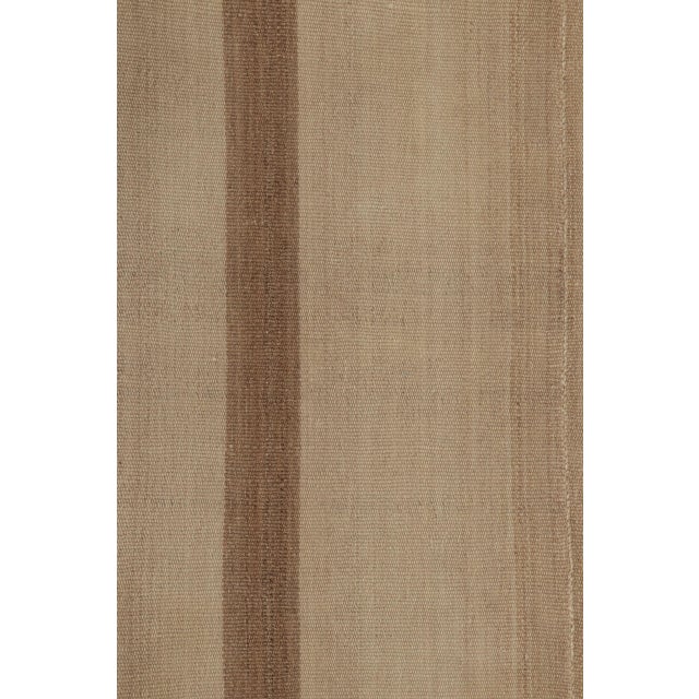Handwoven in wool, this 4x8 Rez Kilim balances a soft neutral field with warm earth-toned bands that frame the design....