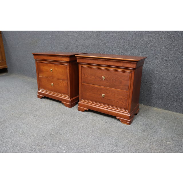Pair of Stickley Louis Philippe style nightstands crafted in cherry wood with a warm reddish-brown finish. Each nightstand...