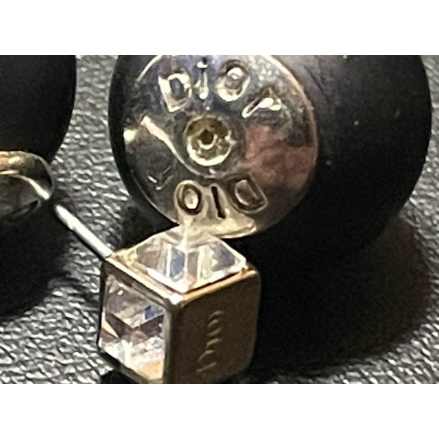 Dior Tribales feature an asymmetrical, double-sided construction where a smaller, decorative front stud is paired with a...
