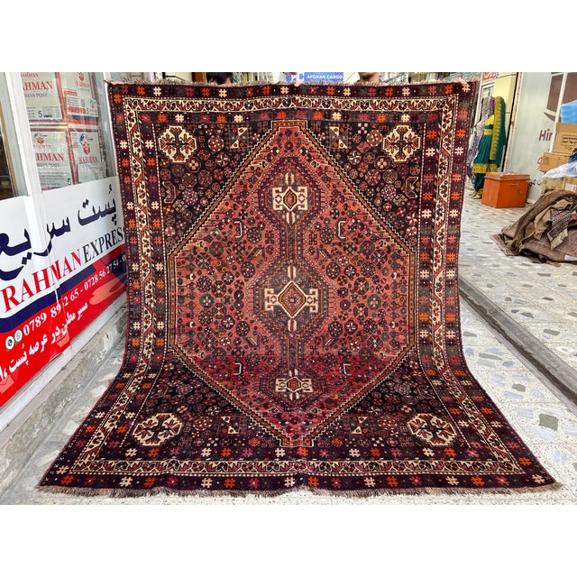 This richly colored Qashqai rug centers on a bold triple-medallion design joined by a traditional pole motif, set against...
