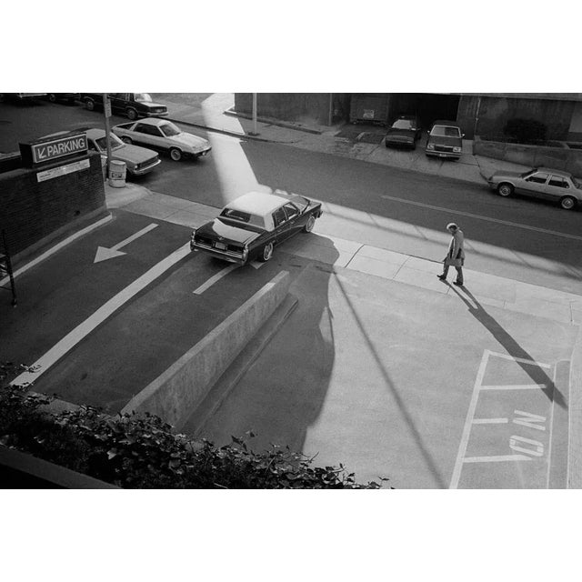 Man Walking Past Parking Lot is a Black and White Print of Hahnumuhle paper available in this size of 8" x 10" in an...