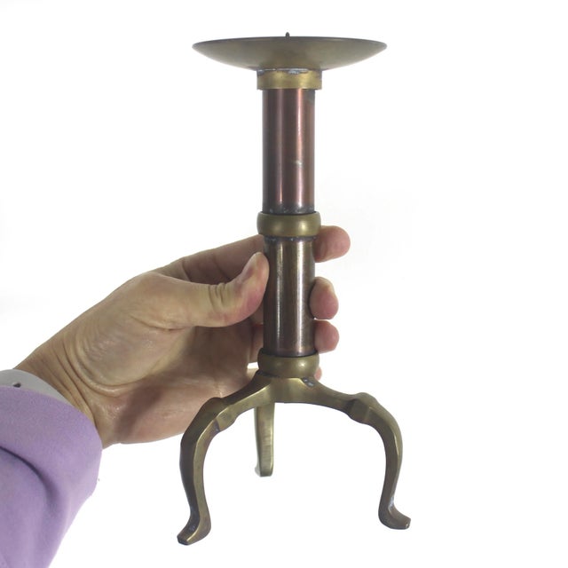 Single brass and copper pillar candle holder with three legs, some corrosion, scratches and patina, shown in the photos....