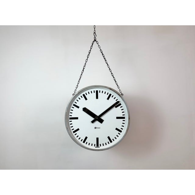This large double sided railway or factory clock was produced by Simlex in Germany during the 1960s. The piece features a...
