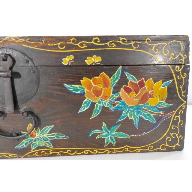 Birds and flowers embellish the front of this wooden trunk along with a scrolling border. Soft shades of yellow, orange...