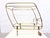 A 1950s bar cart on wheels in a streamlined design with a bottle rack. Brass frame, glass shelves (smoked glass on top,...
