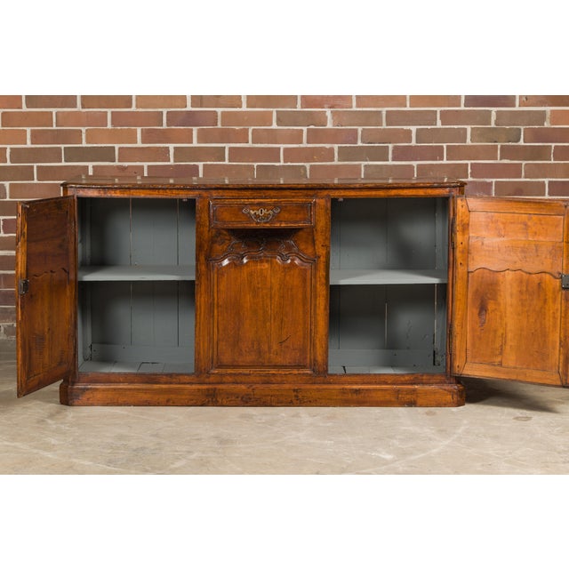 A French walnut buffet from the 19th century with two doors, a single drawer and carved foliage décor. Indulge in the...