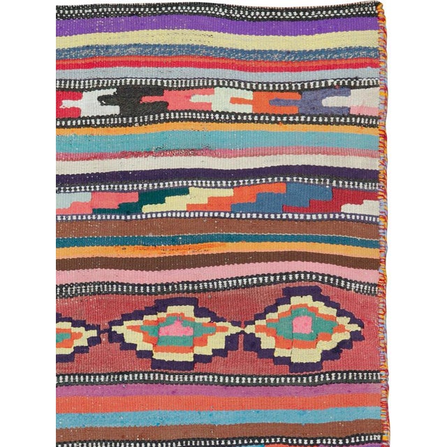 This mid-20th century Persian flatweave kilim rug is a vibrant example of tribal weaving, distinguished by its rhythmic...