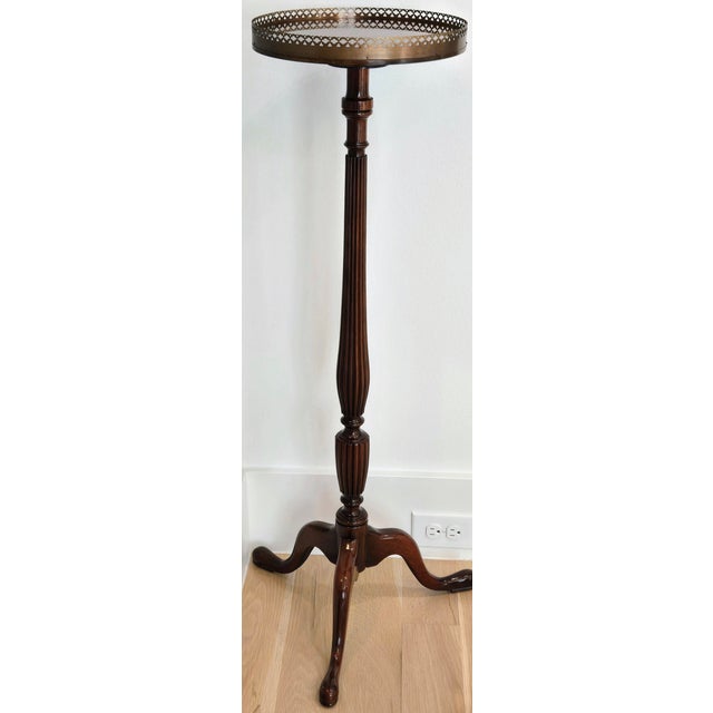 Handsome mid-century mahogany tripod plant stand or petite drinks / side table featuring a round top with a pierced brass...